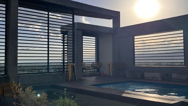A modern outdoor pool area with a view of the ocean, featuring large windows and a wooden deck. - Back to the Neighborhood - Luminous Studio in South Neighborhood with Pool (San Miguel de Tucumán)