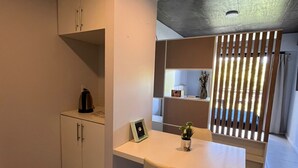 A compact kitchen with a white countertop, a small cabinet, and a kettle. - Back to the Neighborhood - Luminous Studio in South Neighborhood with Pool (San Miguel de Tucumán)