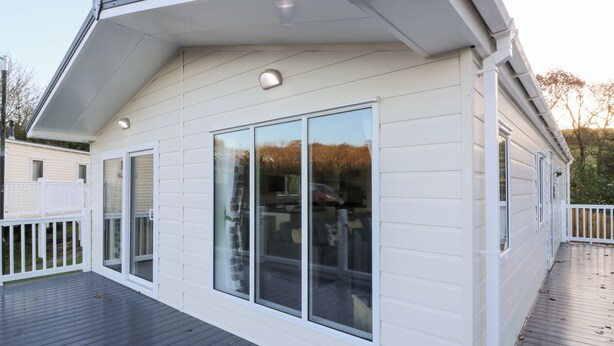 Una casa moderna con una terraza grande, revestimiento blanco y un porche cubierto.