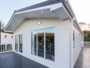 A modern house with a large deck, white siding, and a covered porch area.