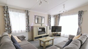 Una sala de estar con chimenea, televisor y un conjunto de sofás.