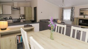 Una cocina moderna con electrodomésticos integrados, un comedor con mesa y sillas de madera, y una sala de estar con sofá y chimenea.