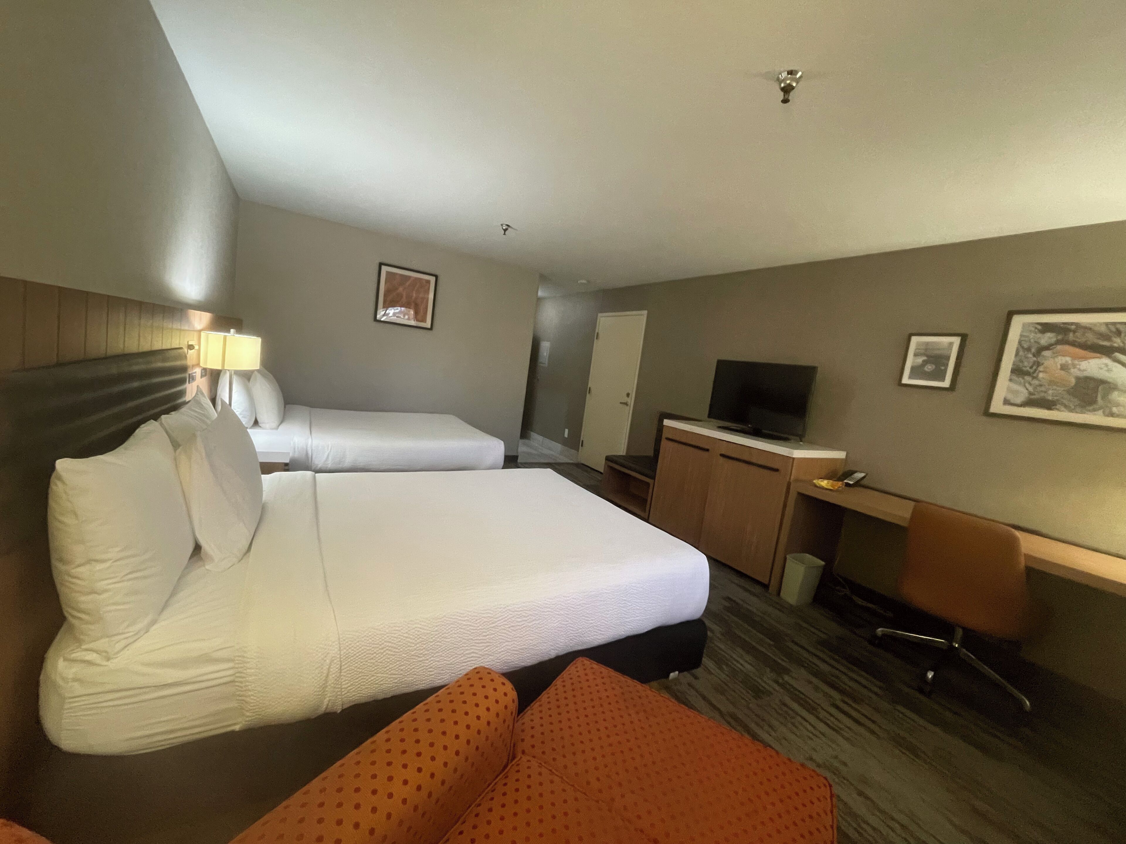 Hotellihuone, jossa on kaksi sänkyä, työpöytä, televisio ja tuoli.