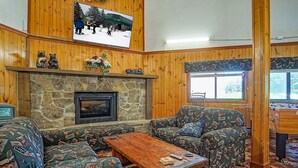 A cozy living room with a stone fireplace, patterned furniture, and a television mounted on the wall. - 2 Br: Snowcrest 214a 2 Bedroom: Indoor Hot Tubs Game Room Easy Slope Access (Snowshoe)