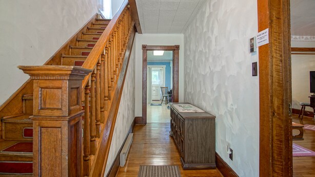 Una escalera de madera que lleva a una habitación con un armario de madera y una alfombra en el suelo.