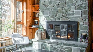 Una habitación acogedora con chimenea de piedra, estantes de madera y una mecedora.