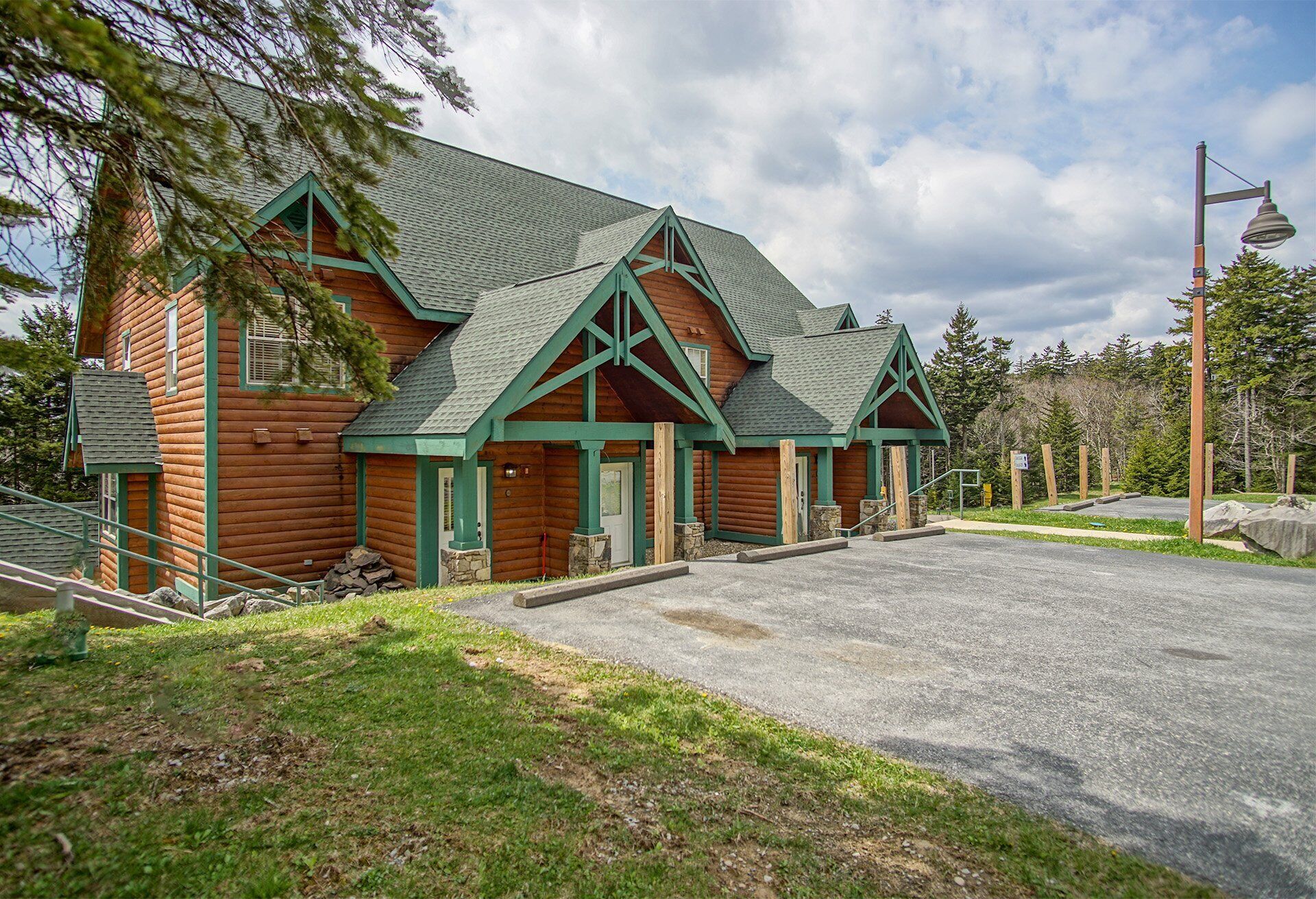 A log cabin with a green roof and a porch.