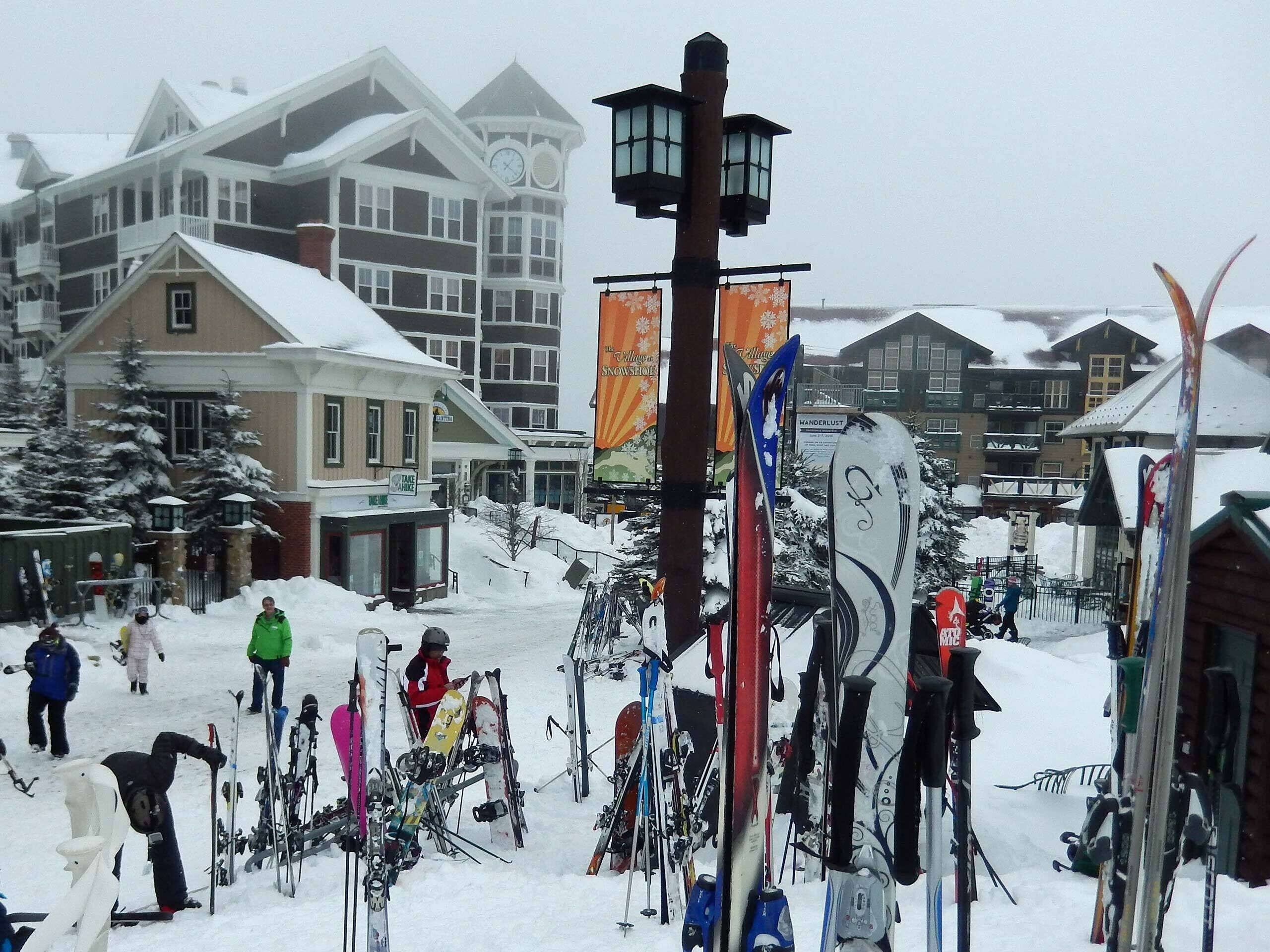 A snowy ski resort with multiple buildings, including a lodge with a clock tower.