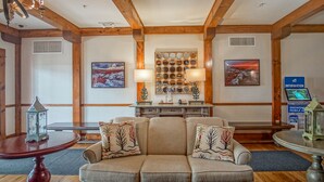 A cozy lobby with a wooden ceiling, a sofa with decorative pillows, a table with a lantern, and wall-mounted artwork. - Highland House #102-104: 2br: 2 Bath (Snowshoe)