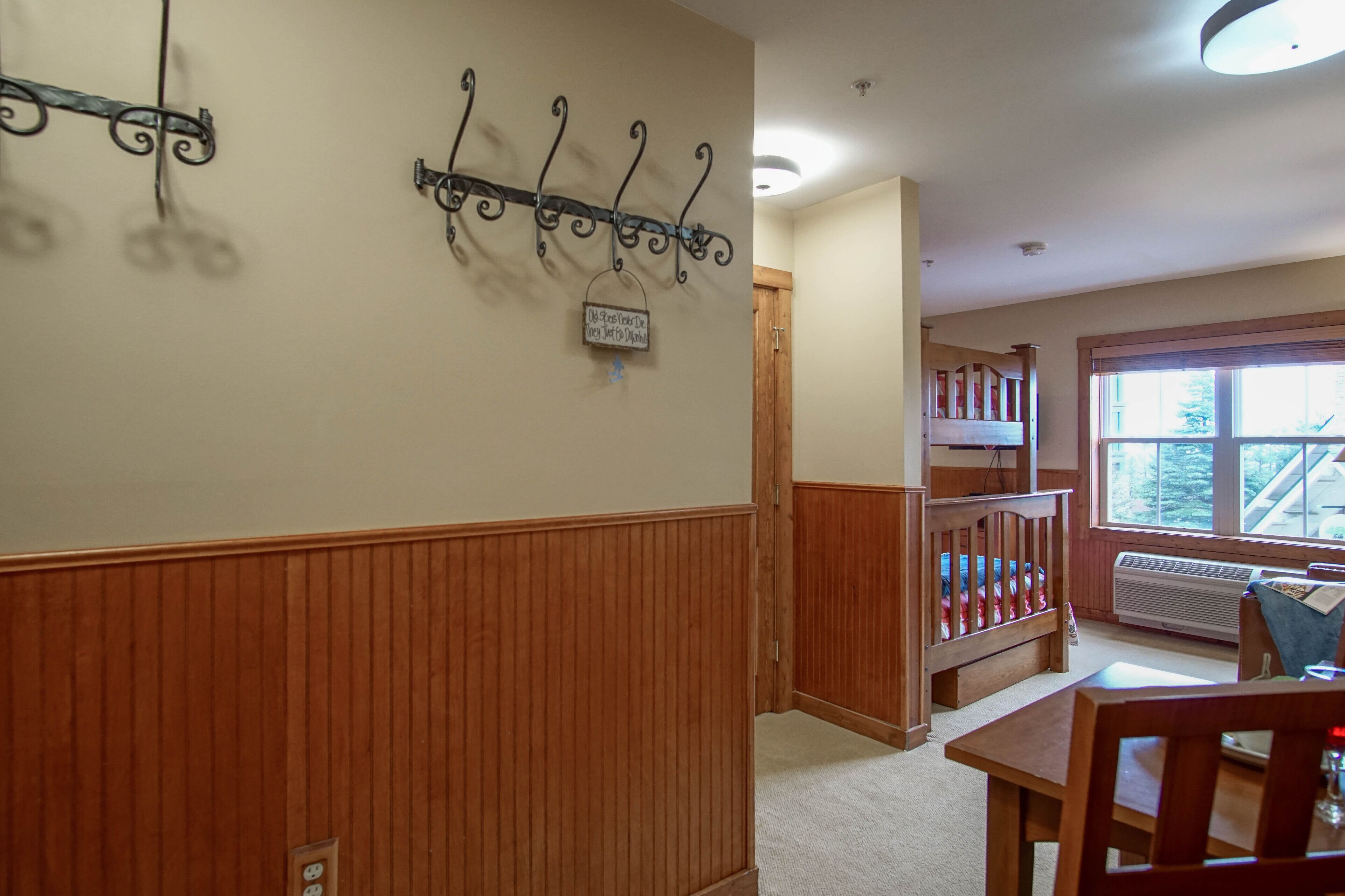 A room with wooden paneling, a bunk bed, a table, and a hanging light fixture.