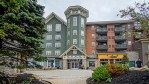 A building with a green facade and a corner tower, a restaurant, and a market. - Highland House #102-104: 2br: 2 Bath (Snowshoe)