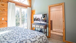 Un dormitorio con una cama grande, un escritorio de madera y un televisor, y una ventana con cortinas.