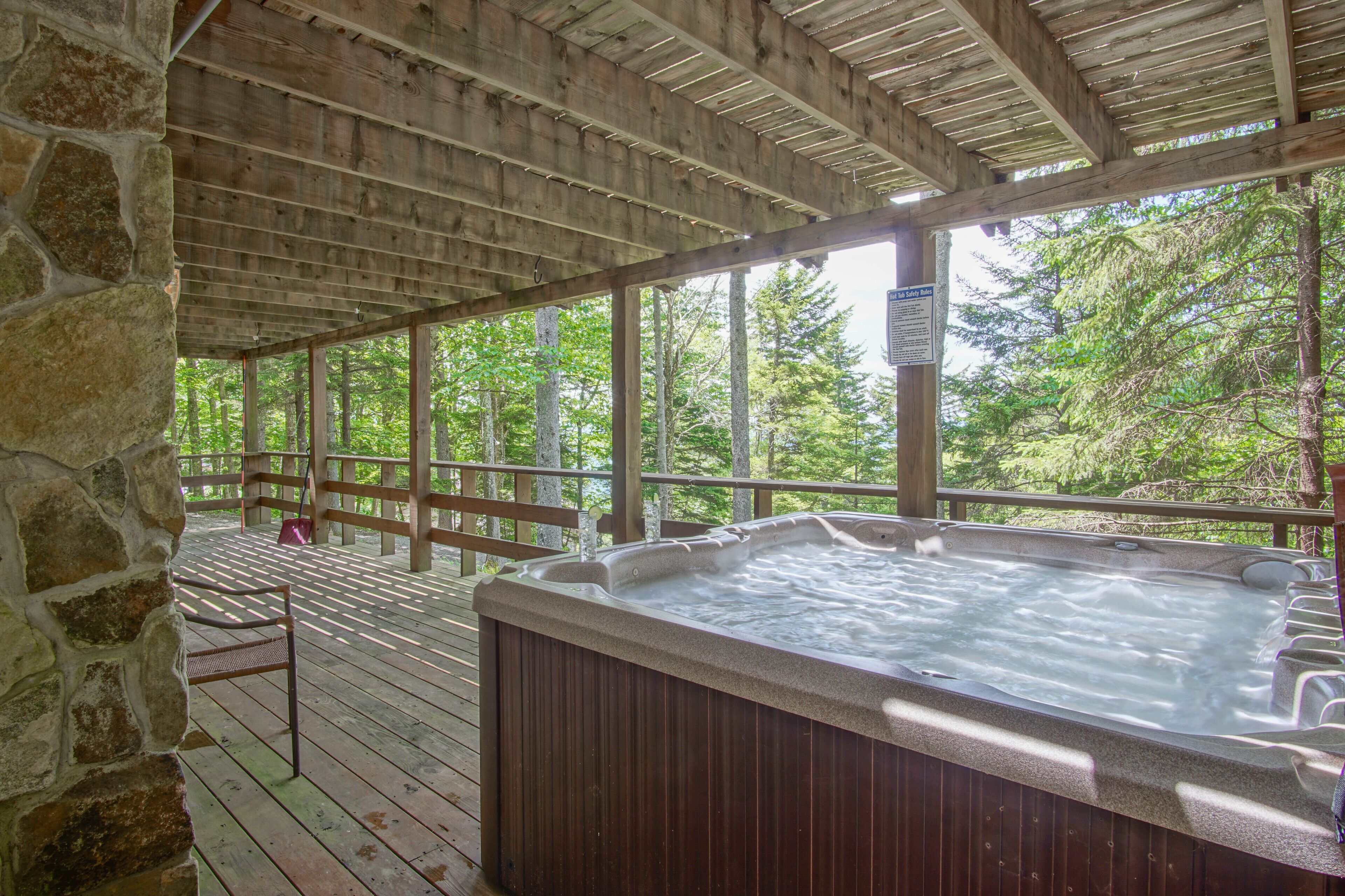 A hot tub in a covered outdoor area with wooden decking and stone walls.