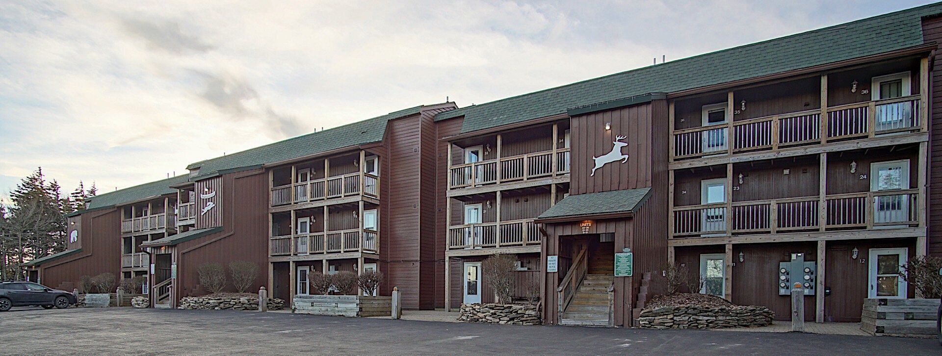 A multi-story wooden building with balconies, a deer logo, and a sign indicating a restaurant.
