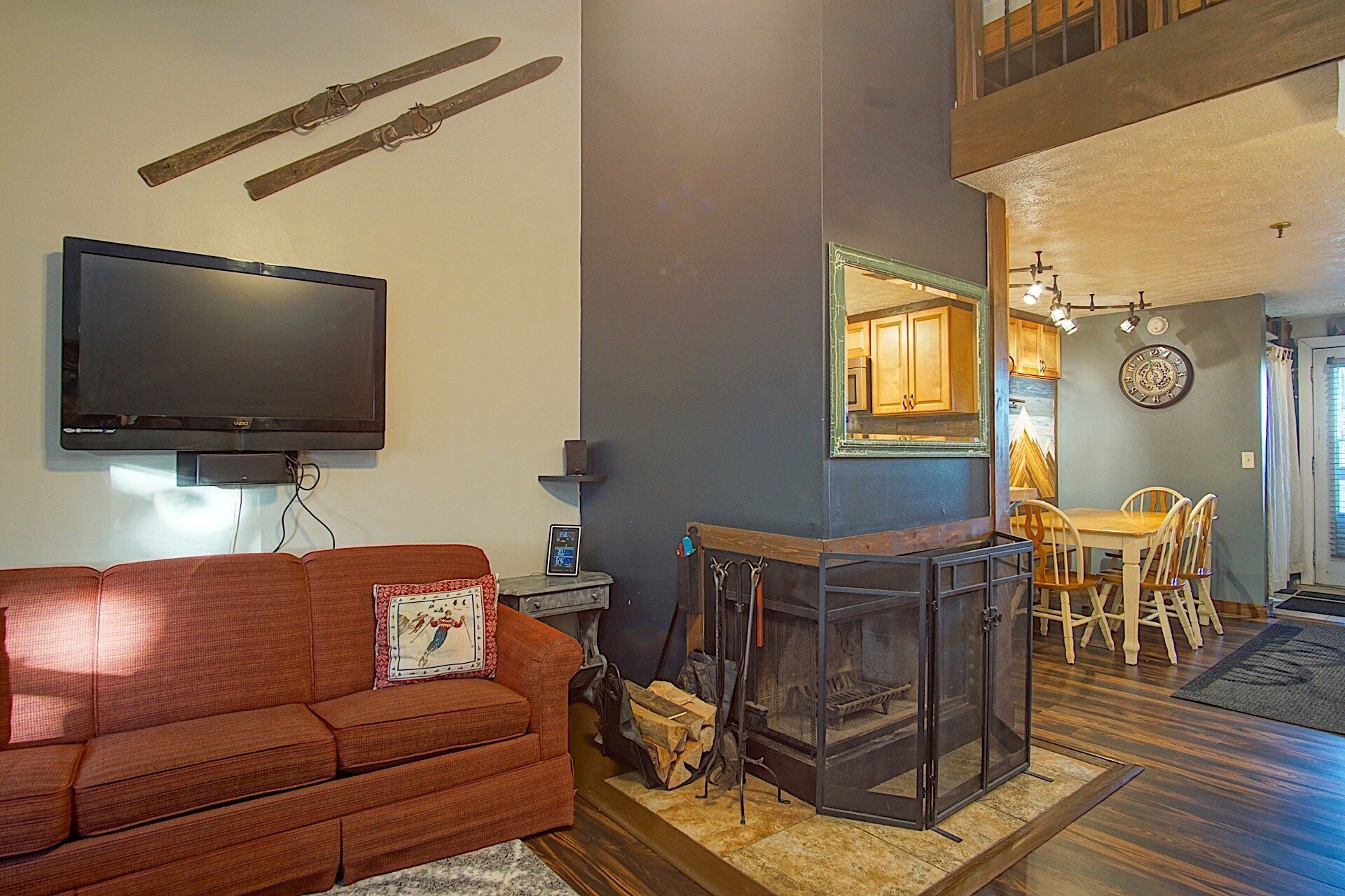 A living room with a fireplace, a television, and a dining area with wooden furniture.