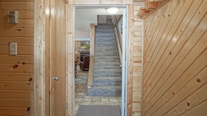 Ein Holzinnenraum mit einer Teppichstufen Treppe, die zu einem Raum mit Kamin führt.