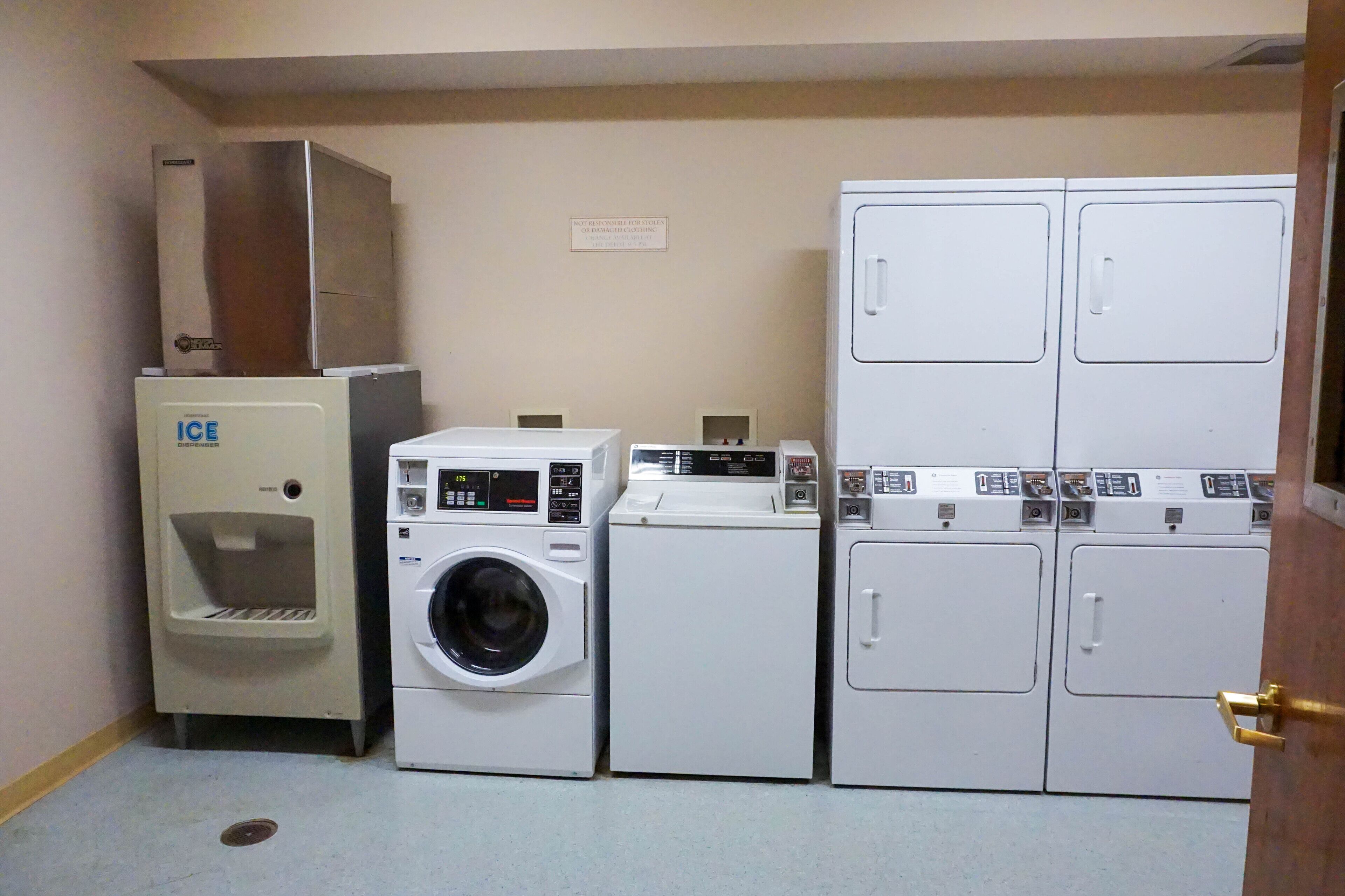 A laundry facility with an ice dispenser, a front-loading washing machine, and stacked top-loading dryers.