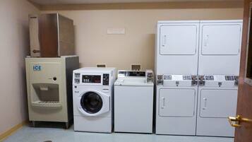A laundry facility with an ice dispenser, a front-loading washing machine, and stacked top-loading dryers.