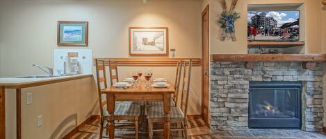 A dining area with a stone fireplace, wooden dining table, and chairs.