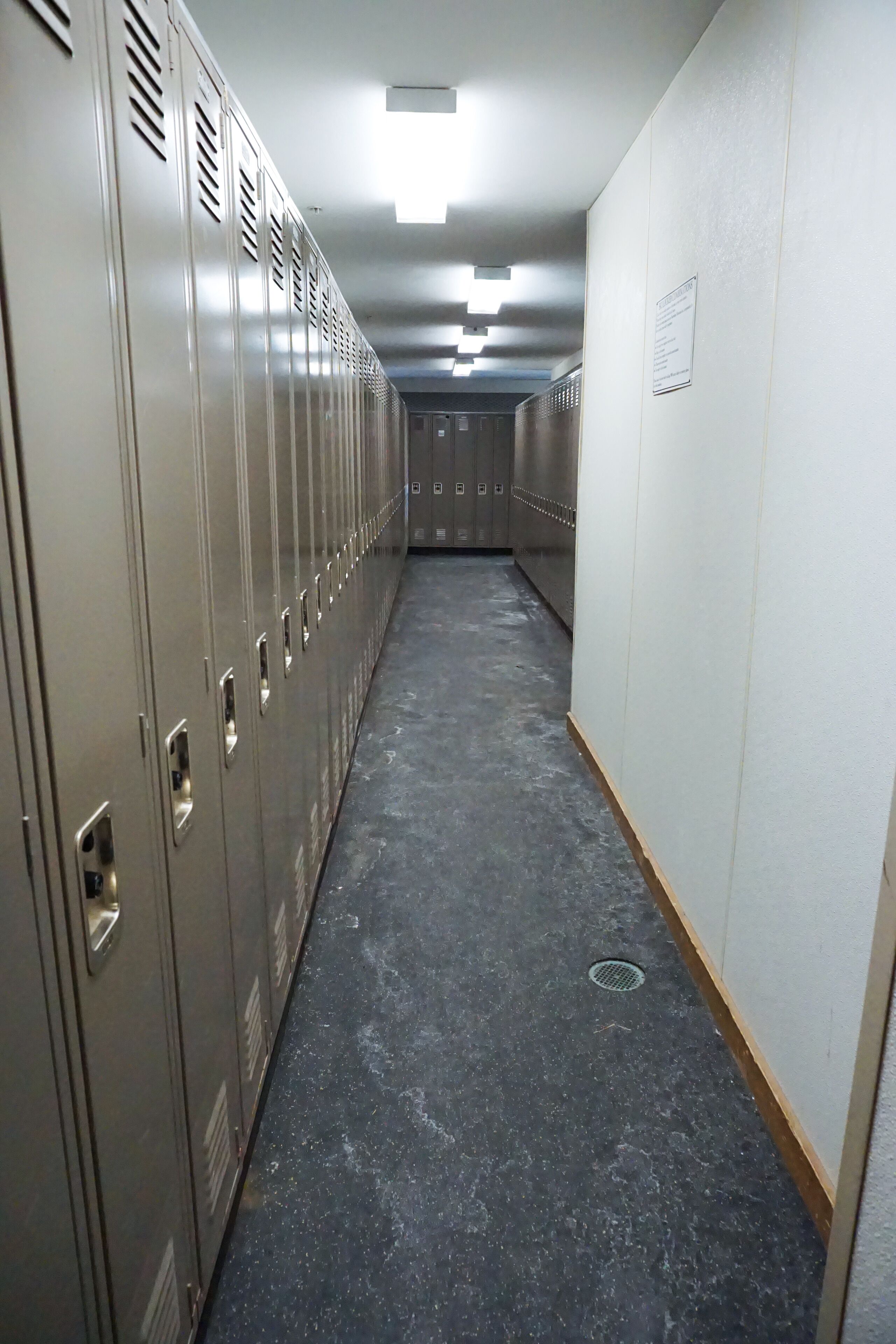 A hallway with lockers and a vent on the ceiling.