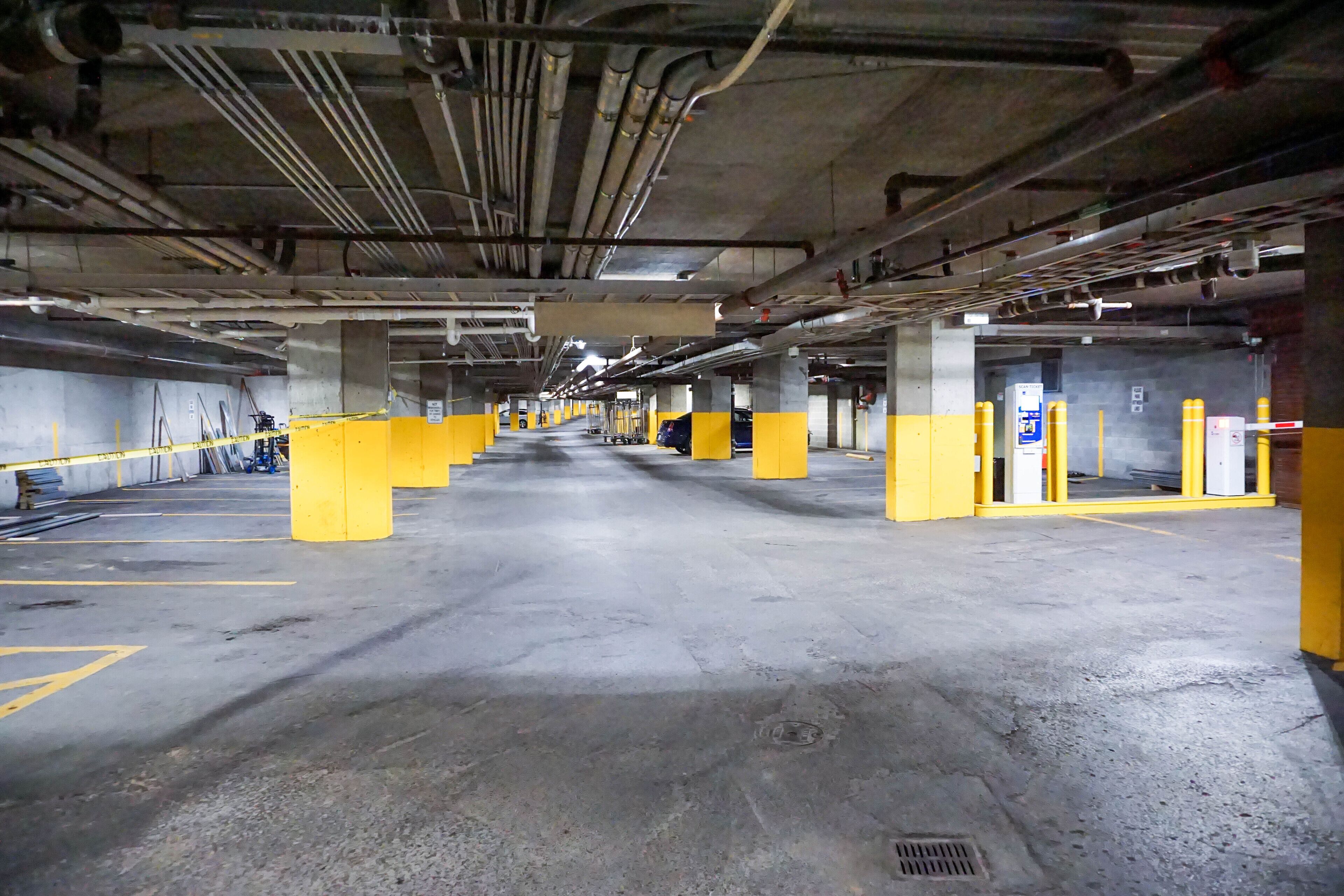Un parking souterrain à plusieurs niveaux, avec des piliers jaunes et des planchers en béton.