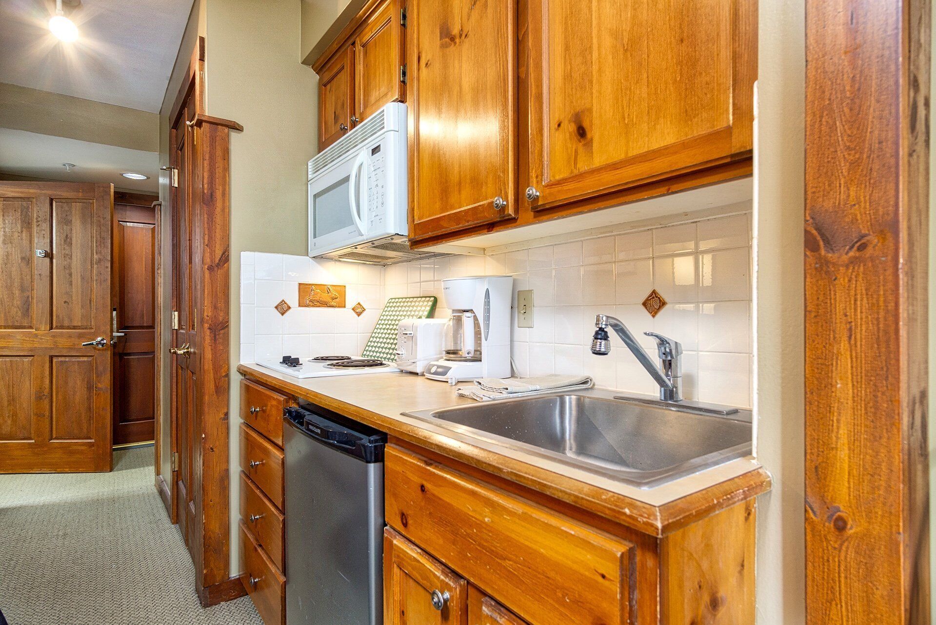 A kitchen with wooden cabinets, a microwave, a coffee maker, and a dishwasher.