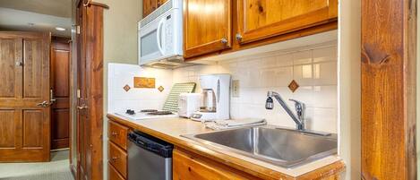 A kitchen with wooden cabinets, a microwave, a coffee maker, and a dishwasher.