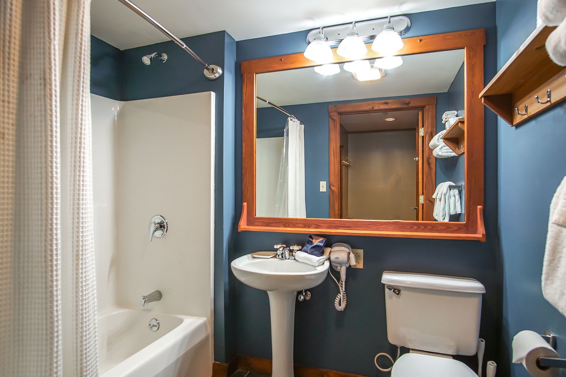 A bathroom with a bathtub, sink, toilet, and a large mirror.