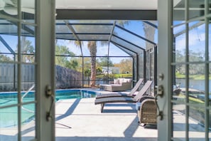 Un espacio exterior techado con piscina, sillas de descanso y vistas del paisaje circundante.