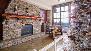 Una sala de estar acogedora con chimenea de piedra, un árbol de Navidad y un sillón de cuero.