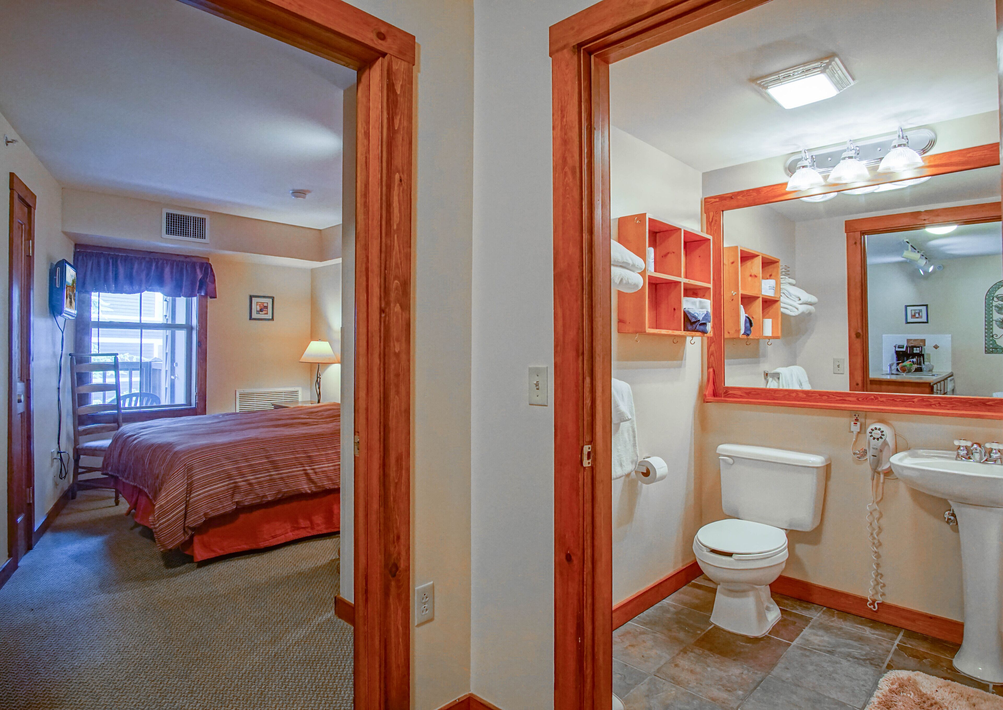 Ein Hotelzimmer mit Bett, Bad mit Toilette, Waschbecken und Spiegel.