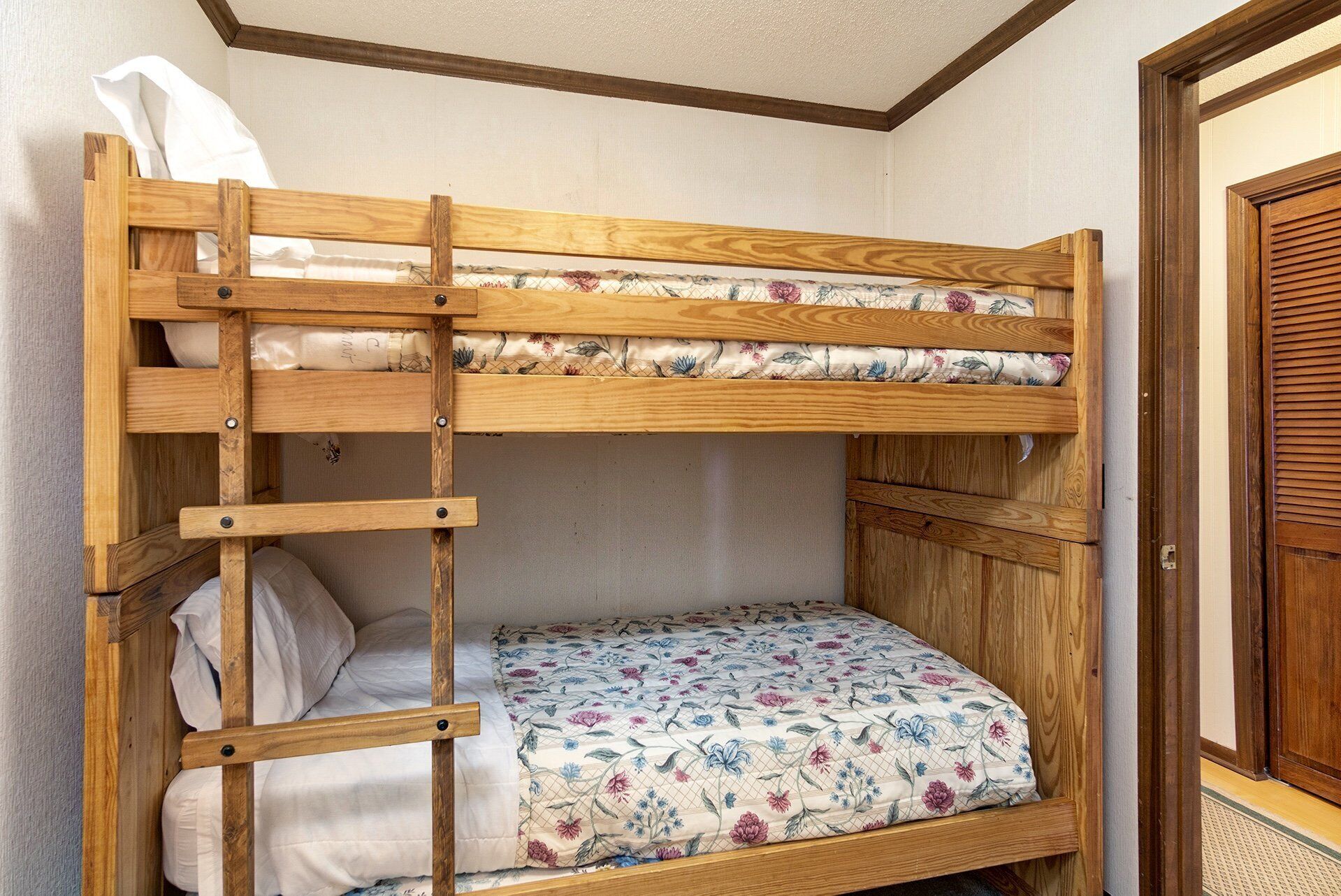 A bunk bed with a wooden frame and floral bedding.