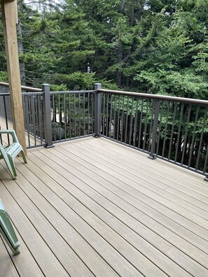 Eine Holzterrasse mit Metallgeländer, umgeben von dichtem Baumbestand.