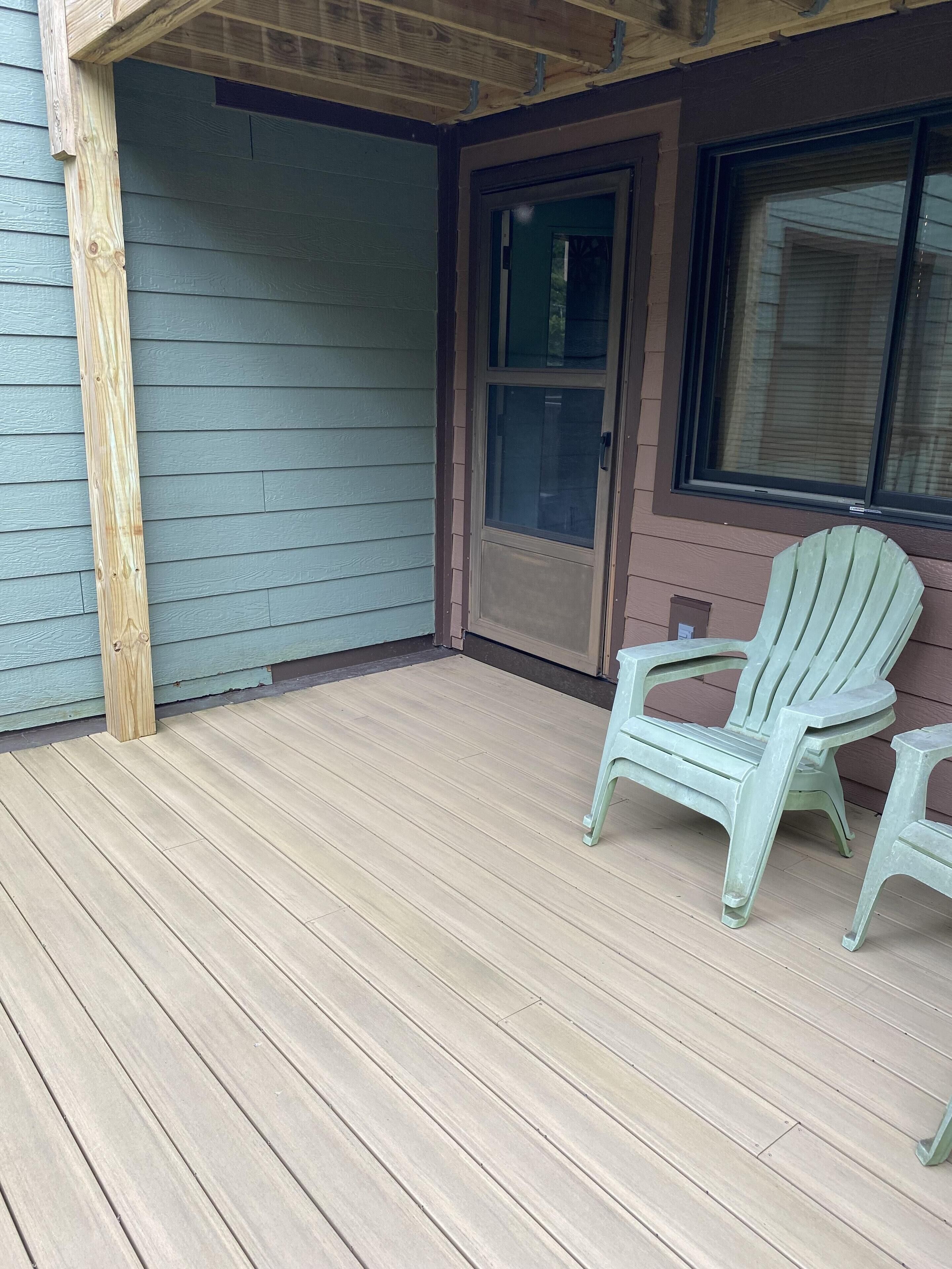 A covered porch with a wooden floor and a door leading to the interior.