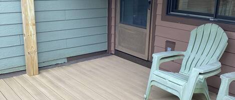 A covered porch with a wooden floor and a door leading to the interior.
