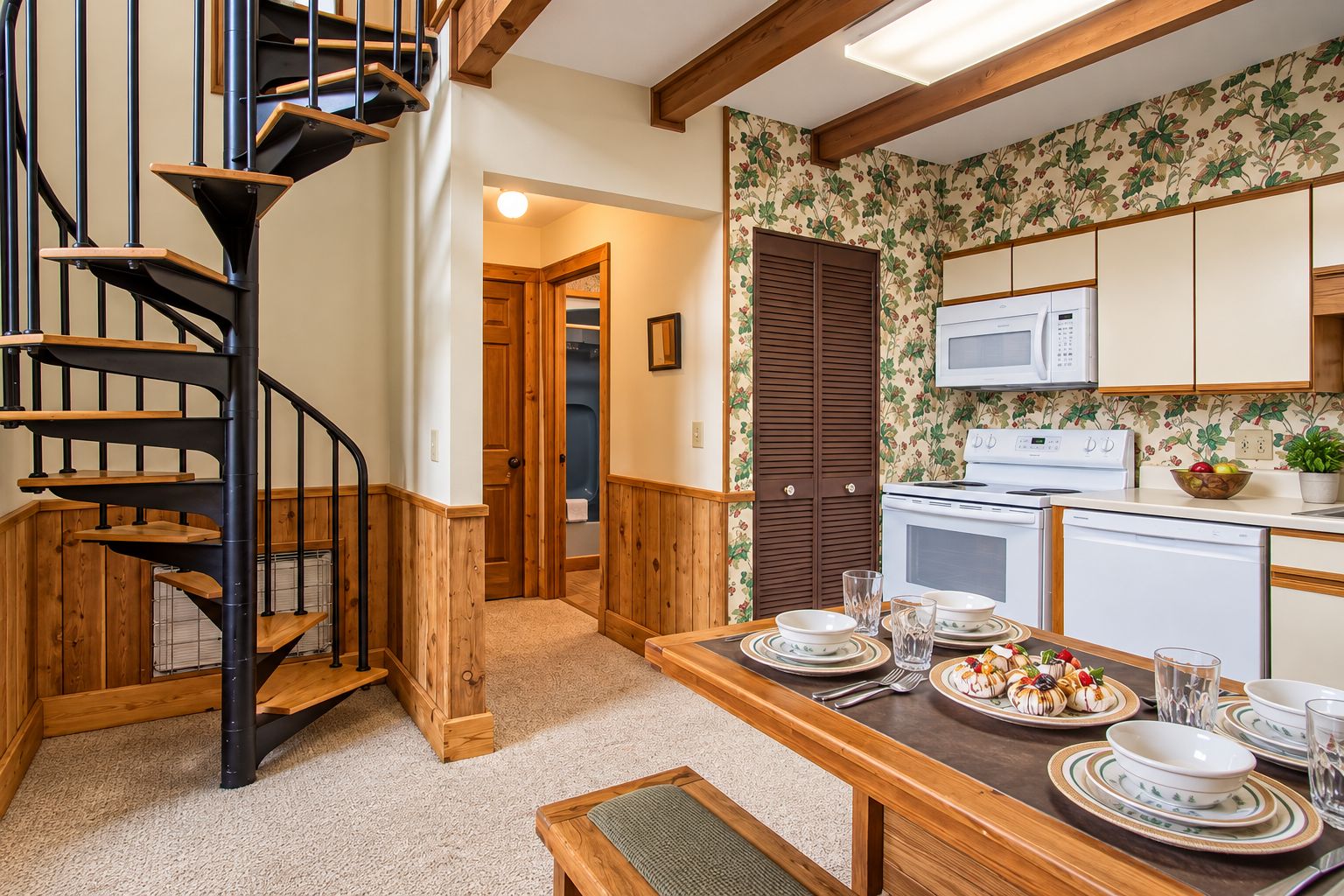 A kitchen with wooden cabinets, a microwave, and a dining area with a table set for a meal.