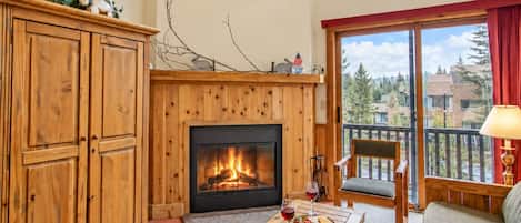 Una sala de estar acogedora con chimenea, muebles de madera y un balcón con vistas.
