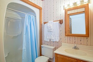 Un baño con ducha, inodoro, lavabo y espejo.