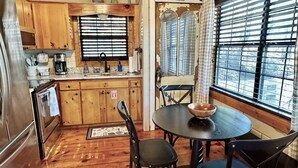A compact kitchen with wooden cabinets, a coffee maker, and a dining area with a round table and chairs. - Stargazer Cabin: Sauna, Rooftop Deck, Fire Pit, Indoor Wood Fireplace, Privacy (Blue Ridge)