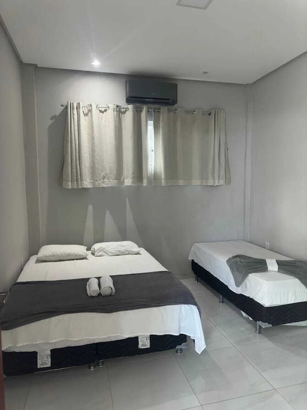 A hotel room with two beds, a ceiling fan, and a window with curtains. - Serra Village Hotel (Ubajara)