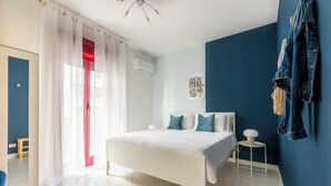 Ein Schlafzimmer mit einem weißen Bett, einer roten Tür und einer blauen Wand.