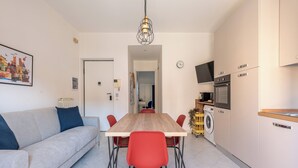 Eine moderne Küche mit einem Holztisch, roten Stühlen, einem grauen Sofa und einer Waschmaschine.
