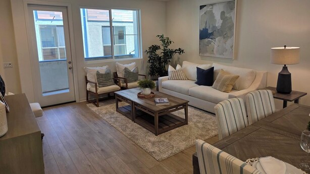 A modern living room with a sofa, armchairs, a coffee table, and a dining table. - Spacious 4-bedroom townhome in beautiful Long Beach with AC (Long Beach)