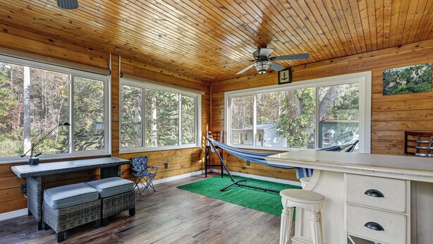 L’intérieur d’un chalet en bois, avec une table à manger, un banc et un hamac.