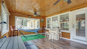 L’intérieur d’un chalet en bois, avec un hamac, un coin bar et de grandes fenêtres.