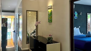 A modern hotel lobby with a reflective black console table, a large mirror, and a decorative wall piece. - Villa Alana (Vaitape)