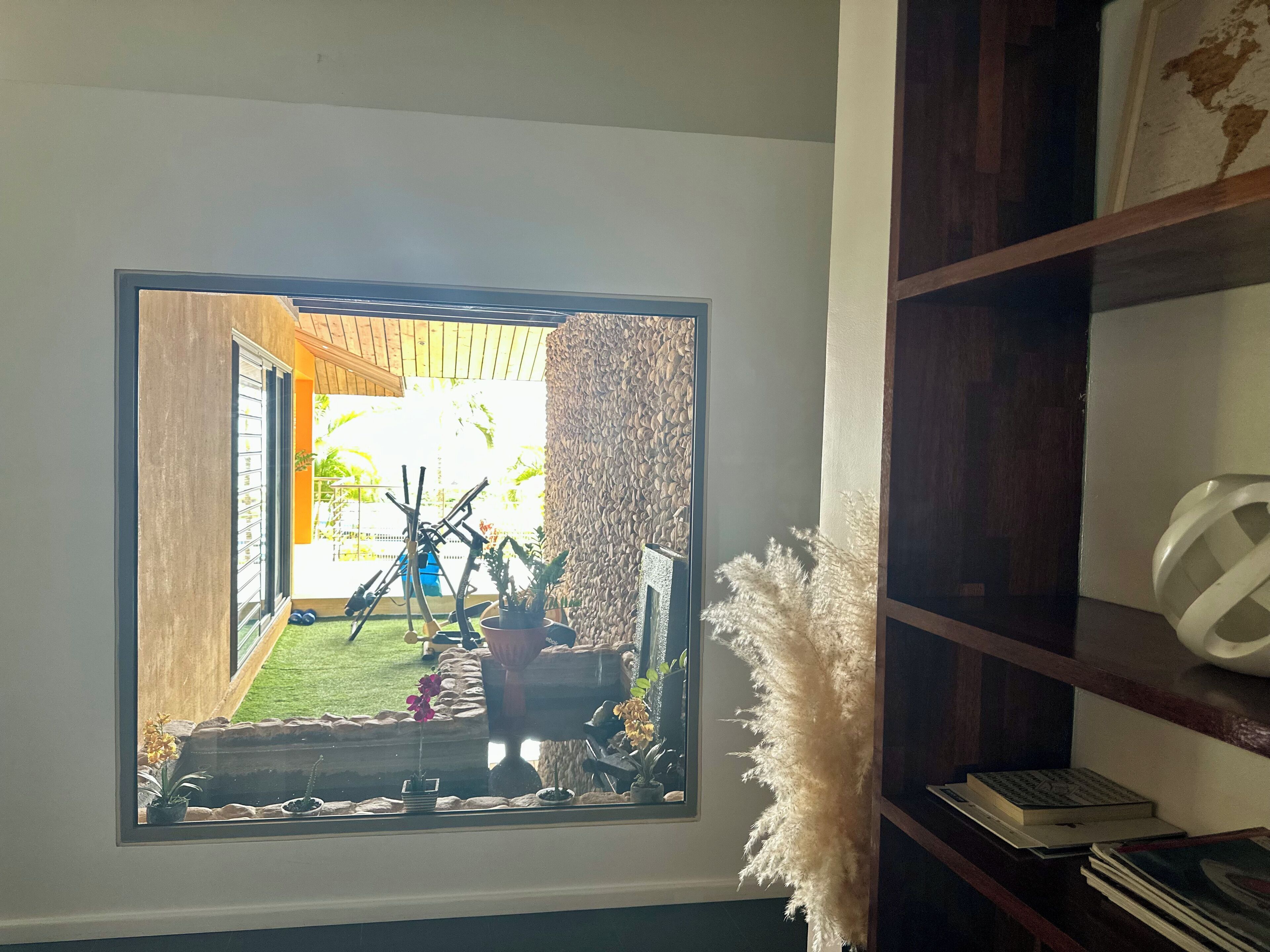 En inramad bild av en trädgård med en träkonstruktion, en krukväxt och en dekorativ vägg.