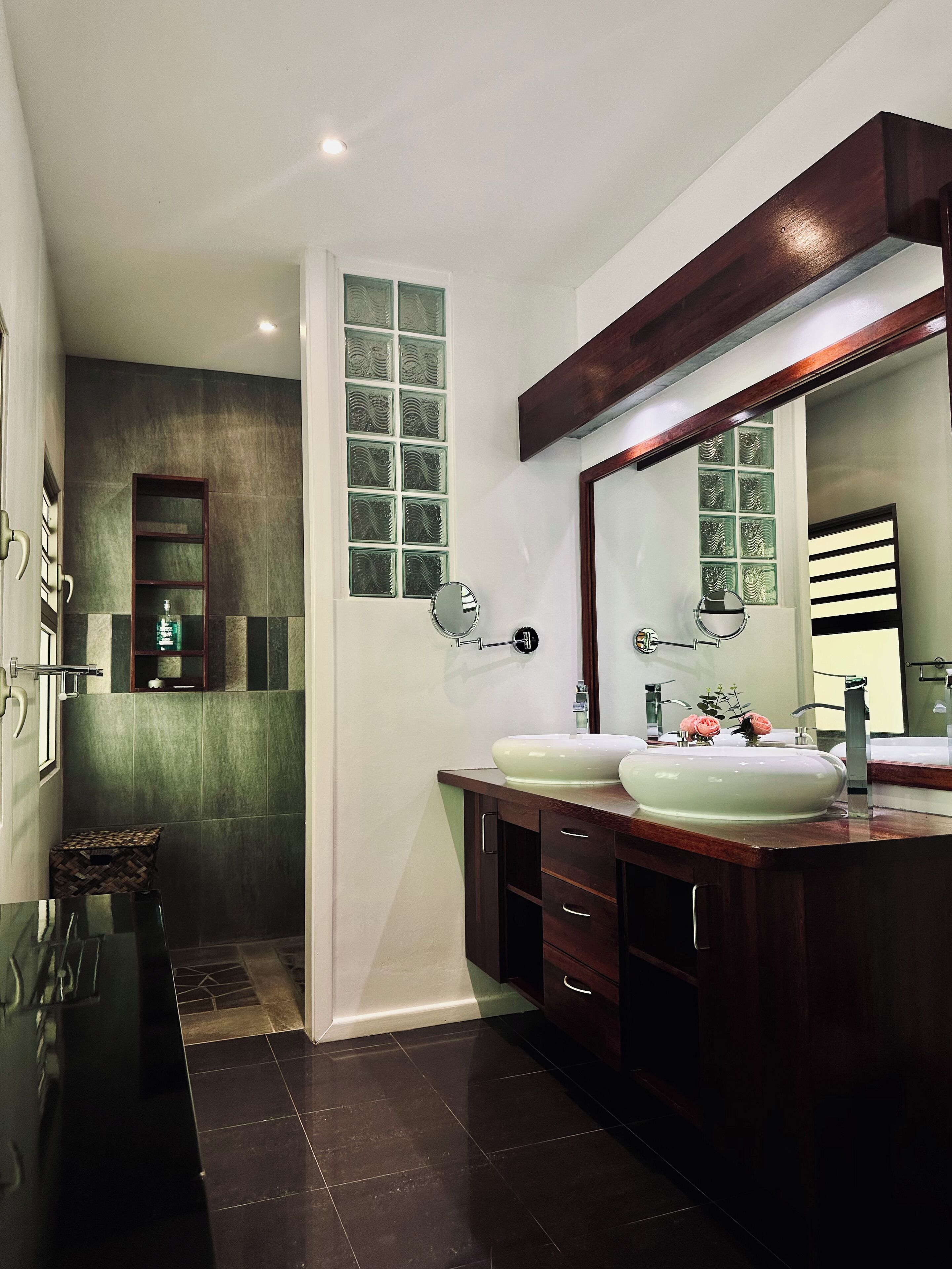 Un baño moderno con dos lavamanos, un espejo grande y una zona de ducha.