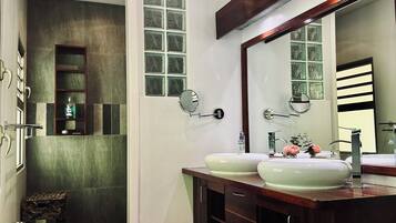 Un baño moderno con dos lavamanos, un espejo grande y una zona de ducha.