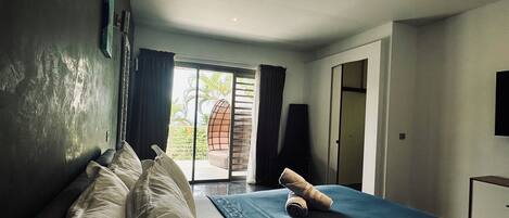 A bedroom with a bed, a window, and a door.